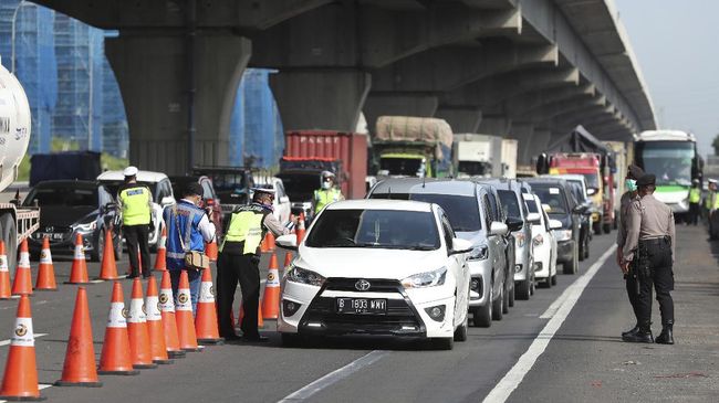 Indonesian police check a car passenger at a checkpoint during the imposition of large-scale restriction to curb the spread of the new coronavirus outbreak on a toll road in Cikarang, West Java, Indonesia, Friday, April 24, 2020. Indonesia is suspending passenger flights and rail service as it restricts people in the world's most populous Muslim nation from traveling to their hometowns during the Islamic holy month of Ramadan because of the coronavirus outbreak. (AP Photo/Achmad Ibrahim)