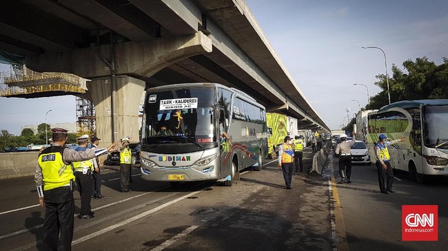 Petugas kepolisian mengecek kendaraan yang melintas di Jalan Tol dari arah Jakarta menuju Cikampek, Jumat (24/6) di Posko Check Point di Gerbang Cikarang Barat, Bekasi, Jawa Barat. Para pengemudi kendaraan yang tidak berkepentingan atau ketahuan hendak mudik diarahkan langsung untun masuk ke Gerbang Tol Cikarang Barat untuk memutat balik kembali ke Jakarta