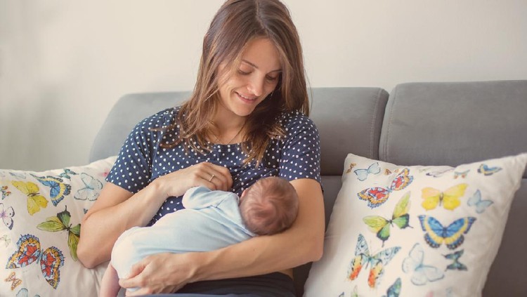 Menyusui Mother breastfeeding a new born baby boy in a hospital room