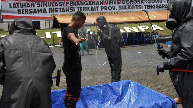 Personel Brimob Polda Sulawesi Tenggara menyemprotkan cairan disinfektan kepada penumpang pesawat saat simulasi penanganan wabah COVID-19 di Mako Brimob Polda Sulawesi Tenggara, Kendari, Sulawesi Tenggara, Rabu (18/3/2020). Simulasi penanganan penumpang pesawat yang diduga terinfeksi COVID-19 tersebut bertujuan meningkatkan kesiapsiagaan personel jika dibutuhkan untuk membantu dalam penanganan masyarakat yang terjangkit virus Corona. ANTARA FOTO/Jojon/wsj.
