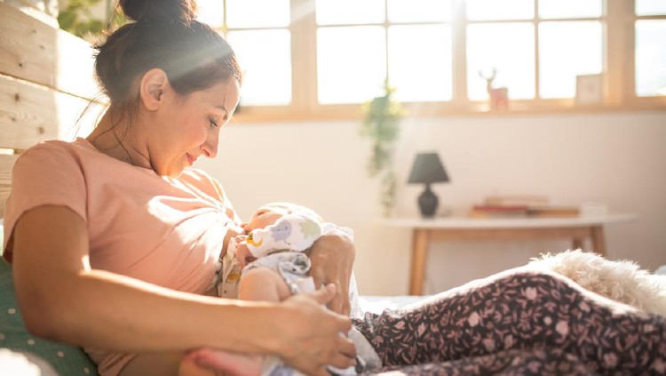 Mother breastfeeding a new born baby boy in a hospital room