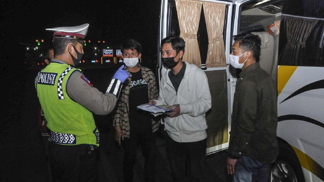 Polisi memeriksa surat tiga orang TKI (Tenaga Kerja Indonesia) dari luar negeri di tol Jakarta-Cikampek, Cikarang, Kabupaten Bekasi, Jawa Barat, Sabtu (25/4/2020). Pada hari kedua penyekatan pemudik di jalan tol masih banyak kendaraan yang tidak mengatur jarak sosial  dan warga yang memaksaan untuk mudik. ANTARA FOTO/Fakhri Hermansyah/pras.