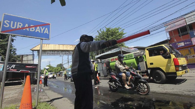Petugas berjaga di Jalan Rungkut Menanggal, Surabaya, Jawa Timur, Minggu (26/4/2020). Kegiatan Operasi Ketupat Semeru 2020 dengan mendirikan pos pemeriksaan (check point) di 17 lokasi akses masuk Surabaya itu dalam rangka pelarangan mudik dan mensosialisasikan aturan-aturan Pembatasan Sosial Berskala Besar (PSBB) di Surabaya yang akan dilaksanakan pada 28 April 2020. ANTARA FOTO/Didik Suhartono/foc.