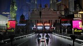 kosong dan sepi, cara las vegas bertahan hidup In this April 18, 2020, photo, a lone worker wearing a mask cleans a pedestrian walkway devoid of the usual crowds as casinos and other business are shuttered due to the coronavirus outbreak in Las Vegas. Nevada's governor closed the glitzy casinos and nightlife attractions in mid-March, leaving much of the famous gambling mecca empty, barricaded and abandoned. (AP Photo/John Locher)