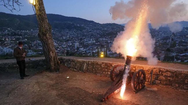 A man fires a vintage canon to signal the breaking of fast shortly after sunset in Sarajevo, Bosnia, Friday, April 24, 2020 during the first day of the holy fasting month of Ramadan. Millions of Muslims have started the holiest month on the Islamic calendar under the coronavirus lockdown or strict social restrictions. (AP Photo/Kemal Softic)
