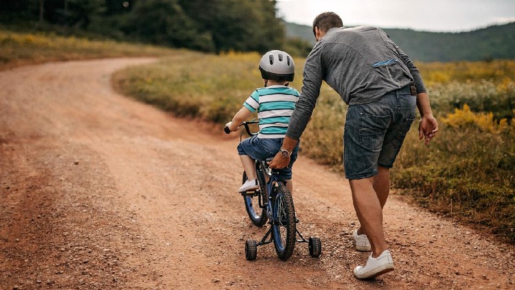 Father helping son to ride a bicycle