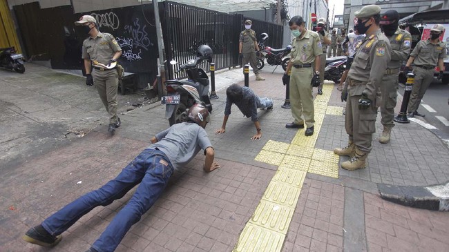 Petugas gabungan memberikan hukuman push up kepada warga yang tidak memakai masker saat razia Pembatasan Sosial Berskala Besar(PSBB) di Kawasan Jalan Fatmawati, Jakarta, Selasa (28/4/2020).  Penertiban tersebut terkait pelaksanaan Pembatasan Sosial Berskala Besar(PSBB) di wilayah Jakarta dan memutus rantai penyebaran COVID 19. ANTARA FOTO/Reno Esnir/foc.