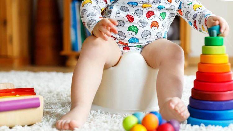 cute six months old baby boy siting on the blue potty early development concept