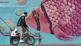 musim panas yang suram FILE - In this April 2, 2020, file photo, a face-mask wearing cyclist pedals past a mural of a tropical fish on the Coney Island boardwalk in the Brooklyn borough of New York. From Cape Cod to California, festivals are being canceled, businesses in tourist havens are looking at empty reservation books, and people who have been cooped up through a dismal spring are worrying summer will bring just more of the same. (AP Photo/Kathy Willens, File)