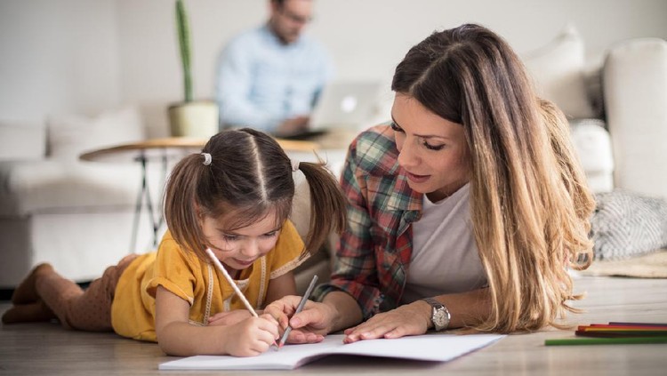 Getting help with my tasks. Little girl working her homework with mother. Focus is on foreground.