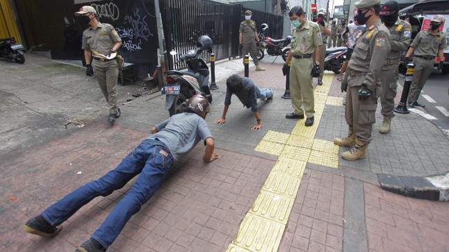 Petugas gabungan memberikan hukuman push up kepada warga yang tidak memakai masker saat razia Pembatasan Sosial Berskala Besar(PSBB) di Kawasan Jalan Fatmawati, Jakarta, Selasa (28/4/2020).  Penertiban tersebut terkait pelaksanaan Pembatasan Sosial Berskala Besar(PSBB) di wilayah Jakarta dan memutus rantai penyebaran COVID 19. ANTARA FOTO/Reno Esnir/foc.
