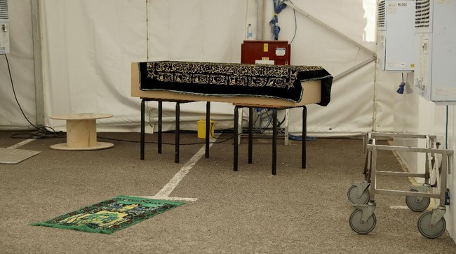 In this photo taken on Friday, April 24, 2020, a view of a coffin containing the body a victim of COVID-19 placed on tables prior to a burial, in a temporary morgue erected for coronavirus victims in the car park of Central Jamia Mosque Ghamkol Sharif in Birmingham, England. The holy month of Ramadan is underway, and the Central Jamia Mosque Ghamkol Sharif should be full of worshippers. But this year, the main arrivals are the dead. While the mosque in the central England city of Birmingham has been closed in response to the coronavirus pandemic, its parking lot has been transformed into a temporary morgue with room for 150 bodies.(AP Photo/Matt Dunham)