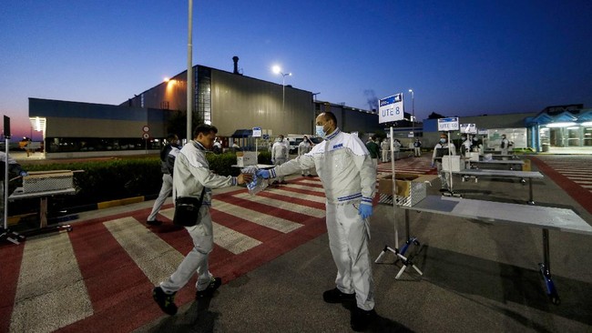 Safety kits with rubber gloves and face masks are distributed to workers at the entrance of the Fiat Chrysler Automobiles plants of Atessa, in Central Italy, Monday, April 27, 2020. FCA is partially reopening factories all over Italy, after the lockdown due to the coronavirus outbreak. (Cecilia Fabiano/LaPresse via AP)