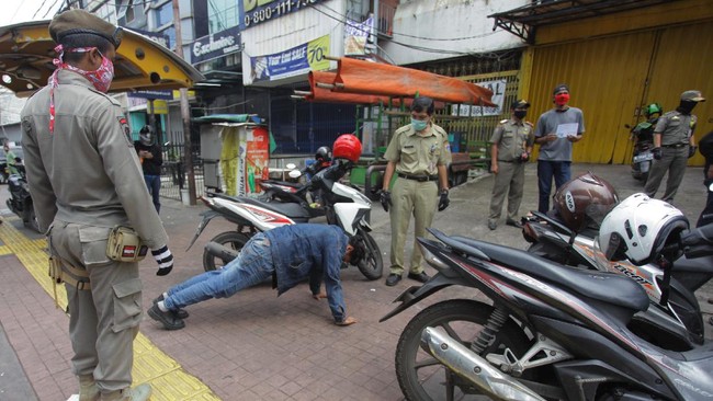 Petugas gabungan memberikan hukuman push up kepada warga yang tidak memakai masker saat razia Pembatasan Sosial Berskala Besar(PSBB) di Kawasan Jalan Fatmawati, Jakarta, Selasa (28/4/2020).  Penertiban tersebut terkait pelaksanaan Pembatasan Sosial Berskala Besar(PSBB) di wilayah Jakarta dan memutus rantai penyebaran COVID 19. ANTARA FOTO/Reno Esnir/foc.