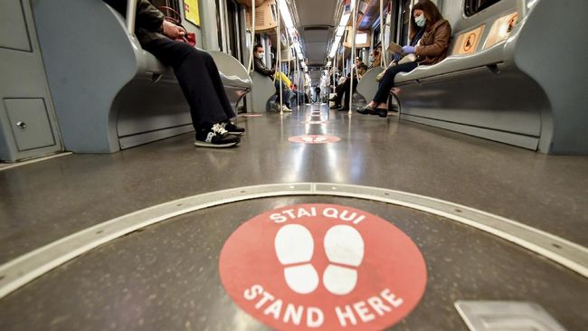 Passengers takes their seats apart from each other as red signs mark the right distances to keep, in a subway train, in Milan, Italy, Monday, April 27, 2020.  Italian factories, construction sites and wholesale supply businesses can resume activity as soon as they put safety measures into place aimed at containing contagion with COVID-19. This concession comes with partial easing of national lockdown restrictions announced Sunday night by Italian Premier Giuseppe Conte. (Claudio Furlan/LaPresse via AP)