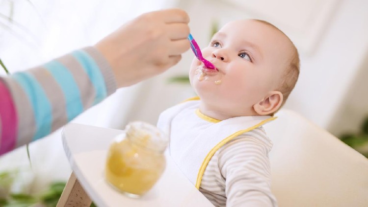 Close-up shot of mother spoon feeding her baby girl.