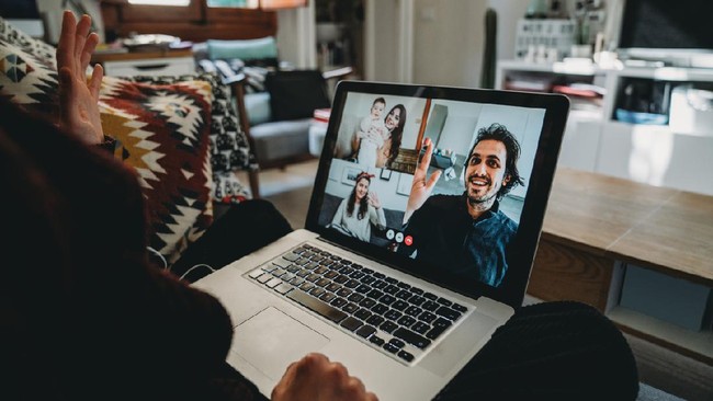 Young woman using a laptop to connect with her friends and parents during quarantine. She's having a video conference during Coronavirus COVID-19 time.