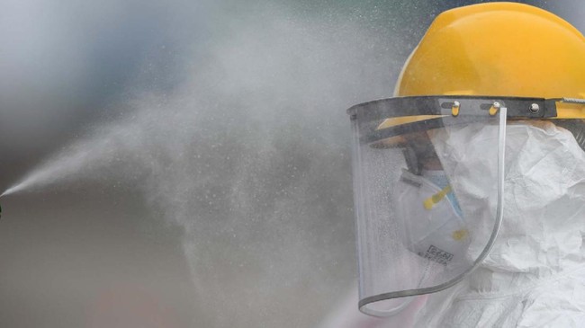 Petugas dari Kantor Kesehatan Pelabuhan (KKP) Kelas I Tanjung Priok menyemprotkan cairan disinfektan ke kepala rekannya usai melaksanakan rapid test atau pemeriksaan cepat COVID-19 terhadap Warga Negara Indonesia (WNI) yang menjadi anak buah kapal Pesiar MV Carnival Splendor saat tiba di Pelabuhan JICT, Tanjung Priok, Jakarta, Kamis (30/4/2020). Sebelum dibawa menuju hotel untuk dilakukan isolasi mandiri selama satu minggu, 375 WNI tersebut terlebih dahulu menjalani rapid test. ANTARA FOTO/Nova Wahyudi/nz