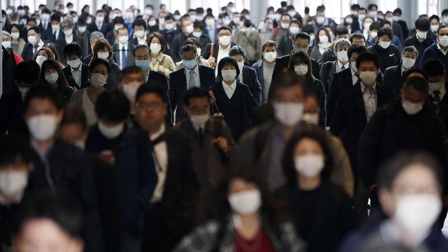 FILE - In this April 27, 2020, file photo, a station passageway is crowded with commuters wearing face mask in Tokyo. Under Japan's coronavirus state of emergency, people have been asked to stay home. Many are not. Some still have to commute to their jobs despite risks of infection, while others are dining out, picnicking in parks and crowding into grocery stores with scant regard for social distancing. (AP Photo/Eugene Hoshiko, File)