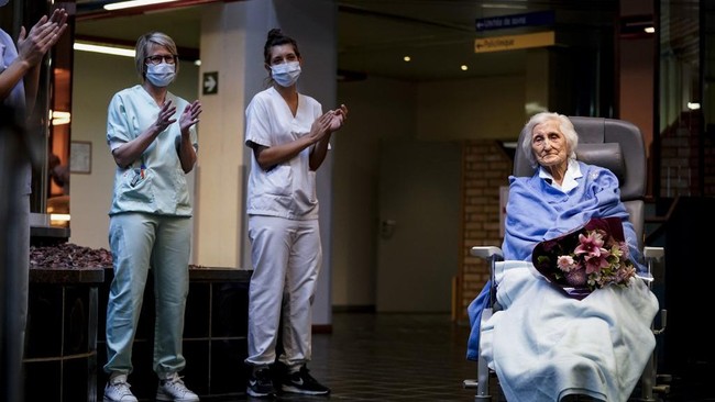 Medical workers clap as Belgian 100 year-old patient Julia Dewilde leaves the Bois de l'Abbaye hospital (CHBA) in Seraing, after being succesfully treated for COVID-19, the disease caused by the novel coronavirus, on April 29, 2020. (Photo by Kenzo TRIBOUILLARD / AFP)