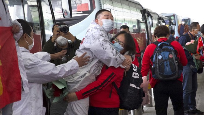 A medical worker from China's Jilin Province, in red, embraces a colleague from Wuhan as she prepares to return home at Wuhan Tianhe International Airport in Wuhan in central China's Hubei Province, April 8, 2020. Within hours of China lifting an 11-week lockdown on the central city of Wuhan, tens of thousands people had left the city by train and plane alone, according to local media reports. (AP Photo/Ng Han Guan)