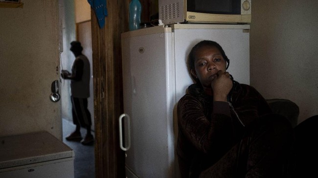 A woman sits inside her room in downtown Johannesburg, South Africa on April 14, 2020. A total of 23 families of blind and disabled foreign nationals living in the dilapidated building and earning a living by street begging have been hard hit by South Africa's lockdown as they are forced to remain indoors. (AP Photo/Bram Janssen)