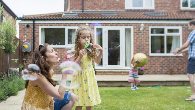 1201844686 A mother and daughter are playing together in the backyard. The are blowing bubbles.