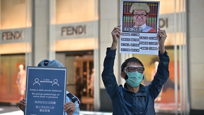 Demo Hong Kong di Tengah Corona A security guard (L) holds up a sign reminding people not to gather in groups of four and to observe social distancing measures next to a pro-democracy supporter (R) holding up a placard as people gather at a shopping mall during a Lunch With You rally in Hong Kong on April 29, 2020. - After four months of calm, protests are cropping up in Hong Kong once more, even as the city hunkers down to beat the COVID-19 coronavirus pandemic. (Photo by Anthony WALLACE / AFP)