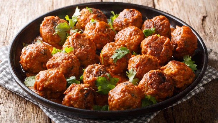Indonesian chicken meatballs in coconut curry sauce with cilantro closeup on a plate on the table. horizontal top view from above