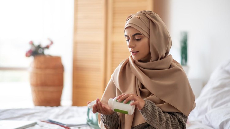 Ilustrasi wanita hijab minum pil