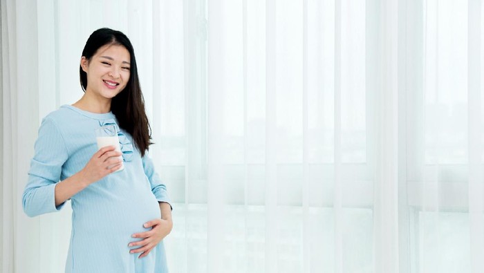 Pregnant woman drinking glass of milk copy space. Young expectant lady enjoying healthy drink. Healthcare, nutrition, vitamins, pregnancy concept