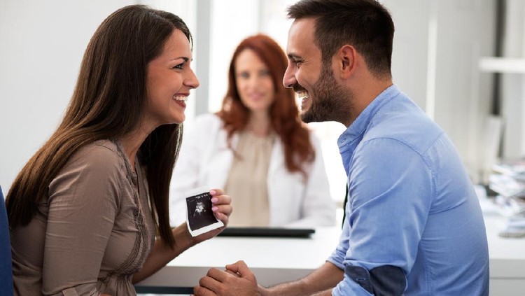 Mother holding ultrasound, husband and wife in a clinic, beautiful family.