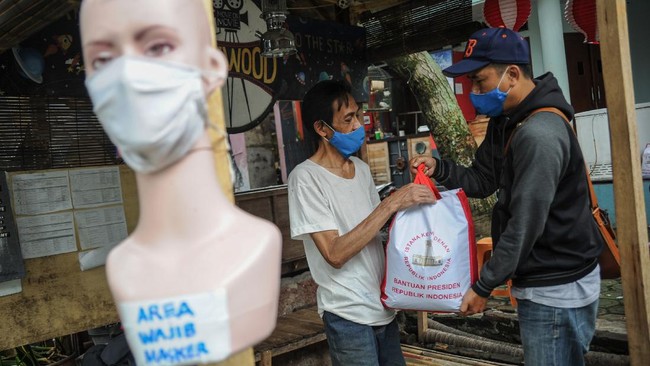 Petugas memberikan bantuan sosial dari Presiden kepada warga di Cibeunying Kidul, Bandung, Jawa Barat, Senin (4/5/2020). Presiden Joko Widodo memberikan paket berupa sembako kepada 10.000 warga di Kota Bandung yang terdampak ekonomi akibat wabah COVID-19. ANTARA FOTO/Raisan Al Farisi/pras.
