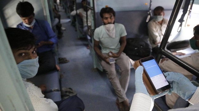 A railway officer collects data of migrant workers sitting inside a special train to return to Agra in Uttar Pradesh state, during a nationwide lockdown to curb the spread of new coronavirus, at a railway station in Ahmedabad, in the western Indian state of Gujarat, Saturday, May 2, 2020. India on Friday ran the first train service for thousands of migrant workers desperate to return home since it imposed a nationwide lockdown to control the spread of the coronavirus. Several states, including Rajasthan, Jharkhand, Bihar, Kerala, Maharashtra, Uttar Pradesh, Punjab and Telangana have demanded special trains for returning workers because they couldn't arrange enough buses. Around 1 million migrant workers from Uttar Pradesh are still stranded in other Indian states, state government spokesman, Awanish Awasthi said. (AP Photo/Ajit Solanki)