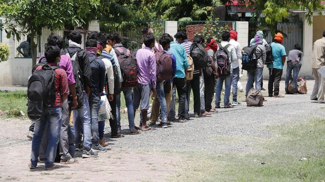 People who arrived from neighboring Madhya Pradesh state stand in a queue to board a bus to be transported back to their native homes in Uttar Pradesh state in Prayagraj, India , Friday, May 1, 2020. The shelter-in-place orders imposed in India on March 24 halted all but essential services, sparking an exodus of migrant workers and people who survive on daily wages out of India's cities and toward villages in rural areas. Prime Minister Narendra Modi is due to announce on Sunday his decision whether to extend the 40-day-old lockdown or gradually ease it to resume economic activity. AP Photo/Rajesh Kumar Singh)