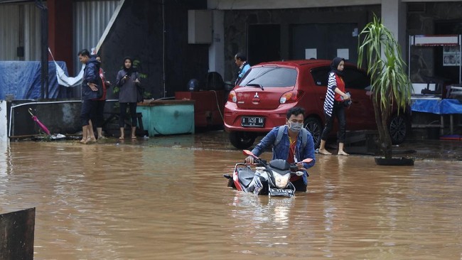 Warga mendorong sepeda motor yang mogok terendam banjir di Kotasari, Grogol, Cilegon, Banten, Senin (4/5/2020). Banjir yang terjadi akibat tanggul Kali Ciore jebol setelah diguyur hujan sejak Minggu (3/5) malam itu mengakibatkan ratusan rumah dan jalan terendam air setinggi 40-110 centimeter. ANTARA FOTO/Asep Fathulrahman/pras.