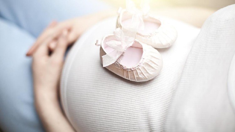 Ibu hamil bayi perempuan Baby shoes on the pregnant woman belly