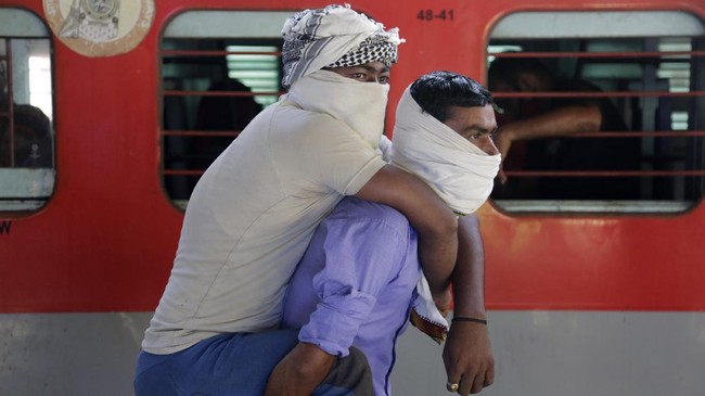 Migrant worker Hira Ali carries his physically disabled brother Muslim Ali on his back as they wait to board a special train to return to Agra in Uttar Pradesh state, during a nationwide lockdown to curb the spread of new coronavirus, at a railway station in Ahmedabad, in the western Indian state of Gujarat, Saturday, May 2, 2020. India on Friday ran the first train service for thousands of migrant workers desperate to return home since it imposed a nationwide lockdown to control the spread of the coronavirus. Several states, including Rajasthan, Jharkhand, Bihar, Kerala, Maharashtra, Uttar Pradesh, Punjab and Telangana have demanded special trains for returning workers because they couldn't arrange enough buses. Around 1 million migrant workers from Uttar Pradesh are still stranded in other Indian states, state government spokesman, Awanish Awasthi said. (AP Photo/Ajit Solanki)