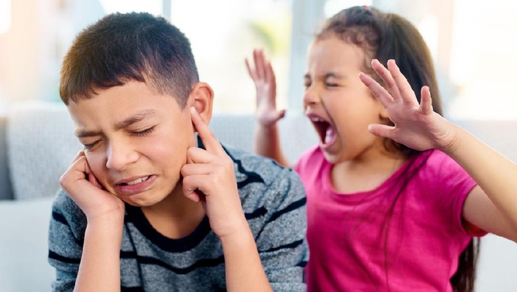 Shot of a little girl screaming in her big brother's ears while playing in the living room at home