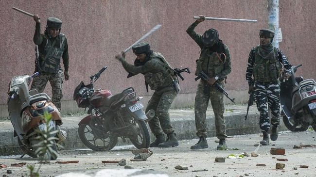 Indian paramilitary soldiers break motorbikes parked outside a college as they clash with students protesting against the alleged rape of a 3-year-old girl in Srinagar, Indian controlled Kashmir, May 14, 2019. The image was part of a series of photographs by Associated Press photographers which won the 2020 Pulitzer Prize for Feature Photography. (AP Photo/Dar Yasin)