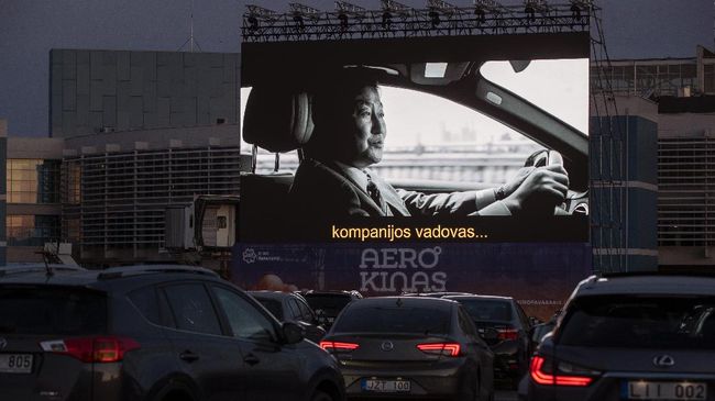 People sit in their cars watching a movie at a new drive-in cinema on a airport apron area, where the planes take off and land, in Vilnius, Lithuania, as regular theaters are closed due to the coronavirus outbreak on Wednesday, April 29 2020. For the first time in history of the Vilnius airport, a drive-in cinema start has been operating in the airport apron area. For the moment, the airport, which had been growing and adding new destinations, is quiet and waiting for international travel restrictions to be lifted. The drive-in cinema will operate one month, starting on April 29th. (AP Photo/Mindaugas Kulbis)