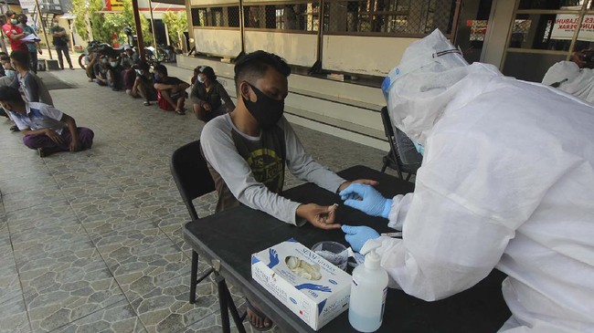Petugas melakukan pemeriksaan cepat COVID-19 (Rapid Test) kepada warga yang terjaring razia di Polres Pelabuhan Tanjung Perak Surabaya, Jawa Timur, Selasa (5/5/2020). Sejumlah orang yang melanggar pembatasan aktivitas malam hari itu menjalani rapid test COVID-19 serta pemeriksaan lebih lanjut setelah terjaring razia yang digelar oleh pihak kepolisian. ANTARA FOTO/Didik Suhartono/hp.