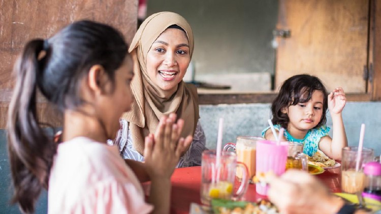 Asian family lunch outdoors, children having fun at table, Father helps feed daughter