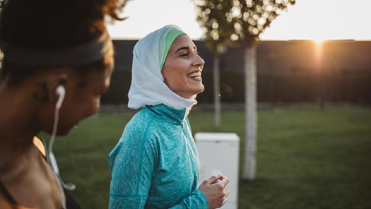 Two young women, different ethnicity ,exercisng outdoor. They are wearing sport clothing.

Getting ready for training.