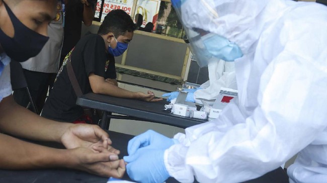 Petugas melakukan pemeriksaan cepat COVID-19 (Rapid Test) kepada warga yang terjaring razia di Polres Pelabuhan Tanjung Perak Surabaya, Jawa Timur, Selasa (5/5/2020). Sejumlah orang yang melanggar pembatasan aktivitas malam hari itu menjalani rapid test COVID-19 serta pemeriksaan lebih lanjut setelah terjaring razia yang digelar oleh pihak kepolisian. ANTARA FOTO/Didik Suhartono/hp.