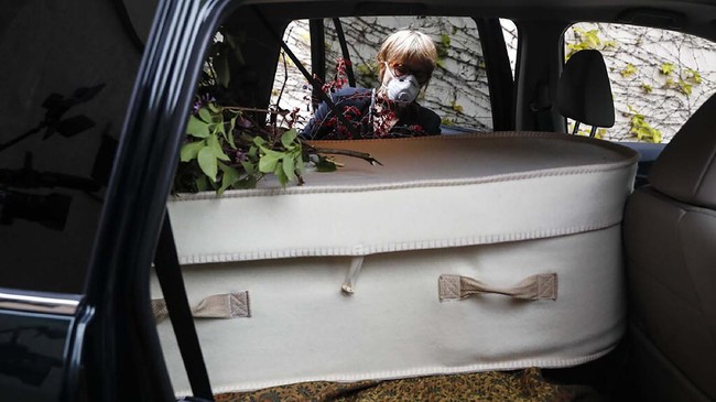 Funeral director Amy Cunningham inspects the casket of Winifred Pardo before leaving Sherman's Flatbush Memorial Chapel, Wednesday, April 29, 2020, in the Brooklyn borough of New York. When 91-year-old Pardo died at last month, her family was in other states and couldn't be with her because of the coronavirus. So the Brooklyn funeral director turned to people in her own neighborhood for help. And people responded. (AP Photo/John Minchillo)