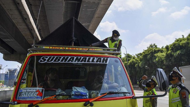 Petugas kepolisian memeriksa bak truk di tol Jakarta-Cikampek, Cikarang Barat, Jawa Barat, Kamis (7/5/2020). Pemerintah menyatakan masyarakat Indonesia tetap dilarang mudik, tapi ada pengecualian bagi ASN, prajurit TNI dan Polri, pegawai BUMN, lembaga usaha, dan LSM yang berhubungan dengan percepatan penanganan COVID-19 serta masyarakat yang keluarganya meninggal atau keluarga sakit, repatriasi, pekerja migran Indonesia, TKI, dan pelajar atau mahasiswa yang akan kembali ke tanah air. ANTARA FOTO/Sigid Kurniawan/aww.