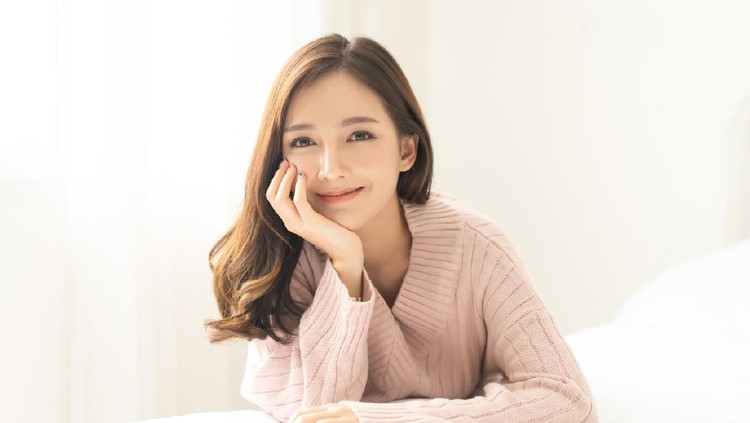 Portrait of young Asian woman smiling friendly and looking at camera in living room.Woman's face closeup. Concept woman lifestyle and winter. Autumn, winter season.