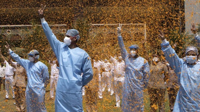 An Indian Air Force helicopter showers flower petals on the staff of INS Asvini hospital in Mumbai, India, Sunday, May 3, 2020. The event was part the Armed Forces' efforts to thank the workers, including doctors, nurses and police personnel, who have been at the forefront of the country's battle against the COVID-19 pandemic. (AP Photo/Rajanish Kakade)