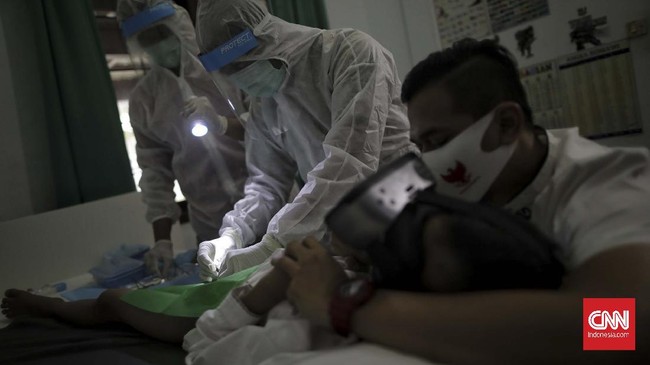 Petugas medis dari Rumah Sunat dr Mahdian menjelaskan prosedur khitan di rumah pasien di Gaga, Ciledug, Tangerang Selatan, Banten, Jumat (8/5/2020). Selama masa pandemi COVID-19 penyedia layanan khitan tersebut melakukan praktik langsung ke rumah pasien dengan menggunakan standar alat pelindung diri (APD) lengkap untuk mendukung pemerintah dalam mencegah penyebaran virus corona. ziel 8thn, siswa kelas 2 sd, orang tua awalnya sempet ragu dengan keinginan anak untuk sunat dimasa pandemi corona. sehingga rencana awal setelah lebaran dengan pikiran wabah telah usai, tapi melihat penyebaran penyakit covid-19 makin panjang akhirny makin parah keluarga mempercepat jadwal, setelah sebelumnya menanyakan prosedur dan keamanan. (CNNIndonesia/Adhi Wicaksono)
